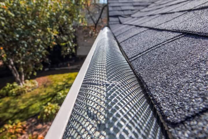 A contractor demonstrating the effectiveness of a gutter guard to a potential client in Durham